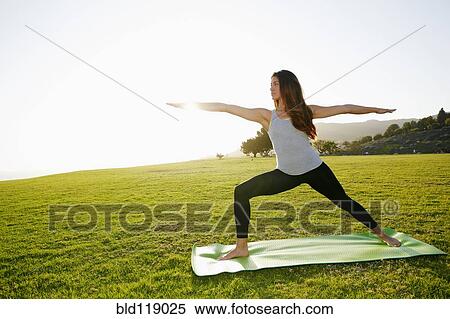 Stock Photography - Mixed race woman practicing yoga in park. Fotosearch