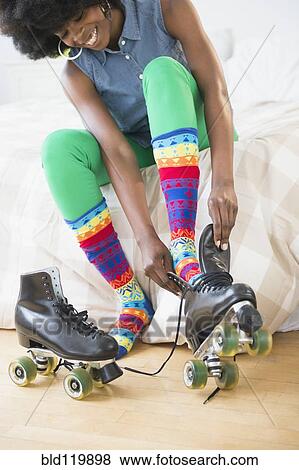 Stock Photo - Mixed race woman putting on roller skates. Fotosearch