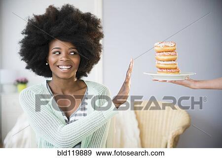Mixed race woman refusing donuts View Large Photo Image Stock Photo - Mixed race woman refusing donuts. Fotosearch