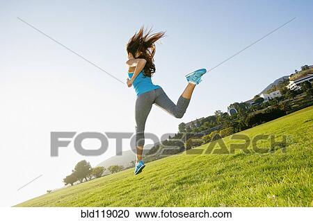 Stock Image - Mixed race woman running in park. Fotosearch