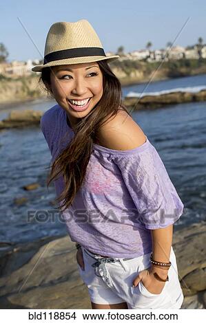 Picture - Mixed race woman smiling on beach. Fotosearch