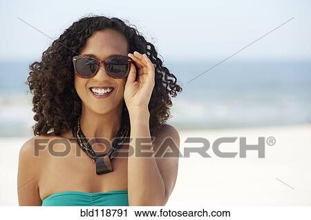 Stock Image - Mixed race woman smiling on beach. Fotosearch
