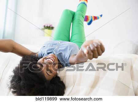 Stock Photo - Mixed race woman smiling on bed. Fotosearch