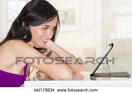 Picture - Mixed race woman using digital tablet. Fotosearch