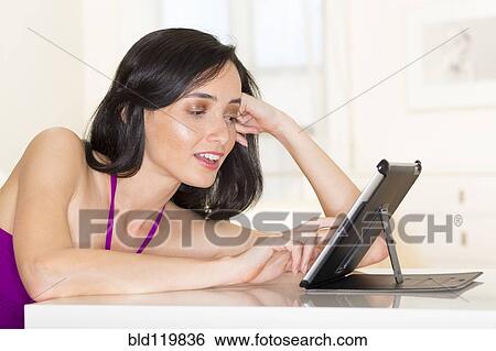 Stock Photograph - Mixed race woman using digital tablet. Fotosearch