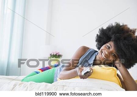 Stock Image - Mixed race woman watching television. Fotosearch