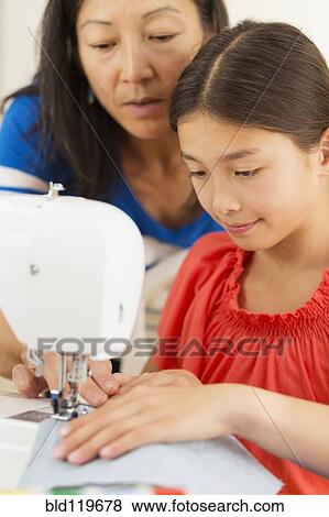Stock Photo - Mother teaching girl to use sewing machine. Fotosearch