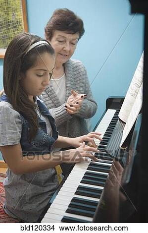 Picture - Older Hispanic woman playing music with granddaughter. Fotosearch