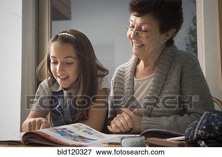 Stock Photo - Older Hispanic woman reading with granddaughter. Fotosearch