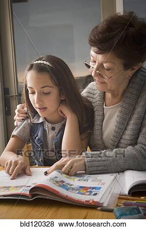 Stock Photo - Older Hispanic woman reading with granddaughter. Fotosearch