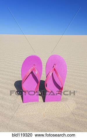 Stock Image - Pink flip flops in sand. Fotosearch