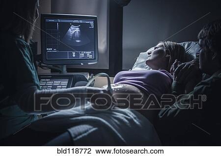 Stock Image - Pregnant couple having sonogram. Fotosearch