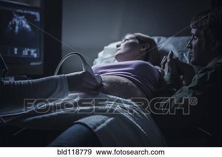 Stock Photo - Pregnant couple having sonogram. Fotosearch