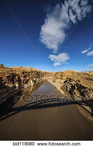 Stock Image - Shadow of bridge over lake in dry landscape, Lake Powell, Utah, United States. Fotosearch