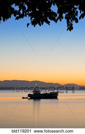 Stock Image - Silhouette of boat on Puget Sound at sunset, Seattle, Washington, United States, . Fotosearch