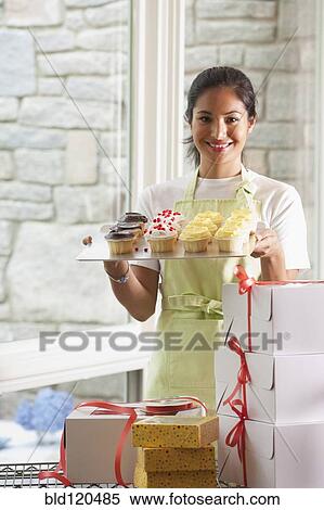 Stock Photography - Smiling baker packing cupcakes. Fotosearch