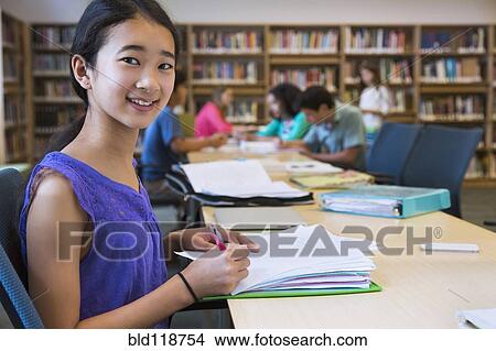 Picture - Student taking notes in library. Fotosearch