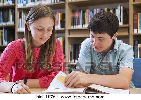 Stock Image - Students reading together in library. Fotosearch