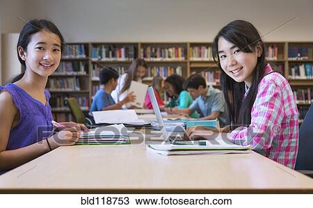 Stock Image - Students working together in library. Fotosearch