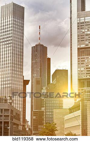 Stock Photo - Sun rising over urban skyscrapers, Frankfurt, Frankfurt, Germany. Fotosearch