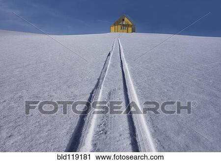 Stock Image - Tire tracks leading to house in snowy landscape. Fotosearch
