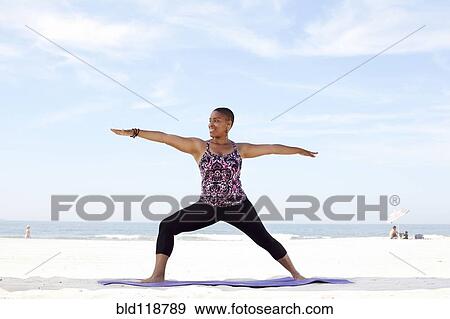 Stock Photo - Woman practicing yoga on beach. Fotosearch