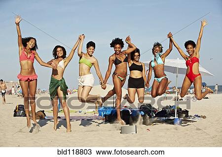 Stock Image - Women jumping for joy on beach. Fotosearch