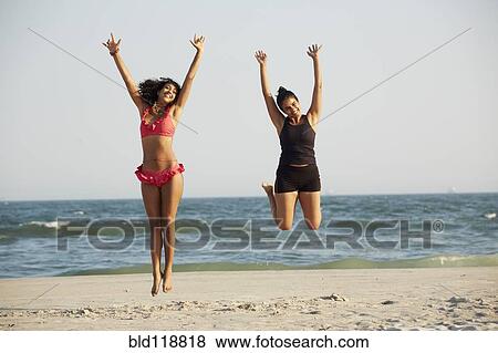 Stock Photo - Women jumping for joy on beach. Fotosearch