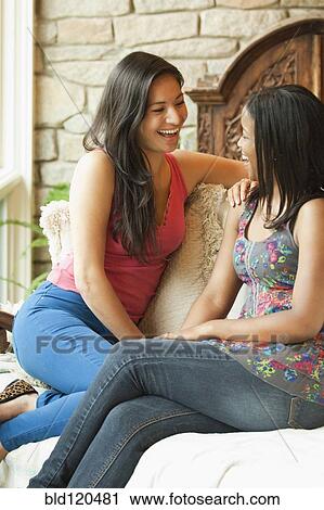 Stock Image - Women laughing together on sofa. Fotosearch