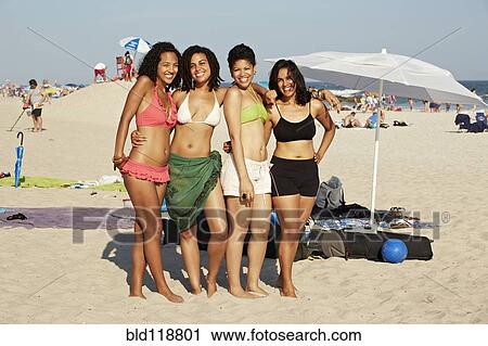 Stock Image - Women smiling together on beach. Fotosearch