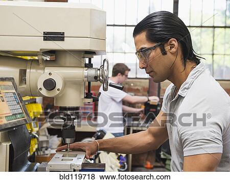 Stock Photo - Workers using machinery in machine shop. Fotosearch