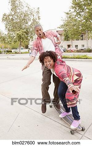 Stock Image - African American couple playing on skateboard. Fotosearch