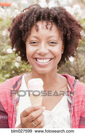 Stock Photo - African American woman eating ice cream. Fotosearch