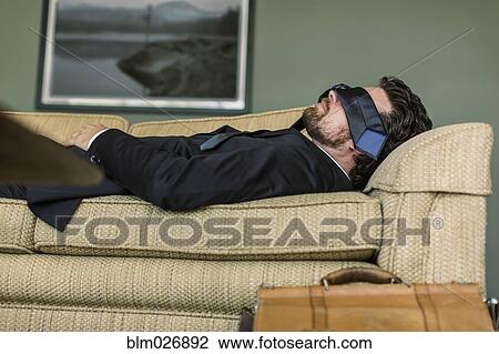 Stock Image - Caucasian businessman napping on sofa. Fotosearch