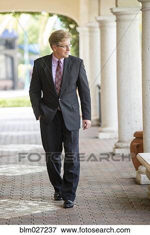 Stock Photo - Caucasian businessman walking in colonnade. Fotosearch