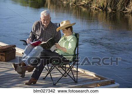 Caucasian couple reading on dock View Large Photo Image Stock Image - Caucasian couple reading on dock. Fotosearch