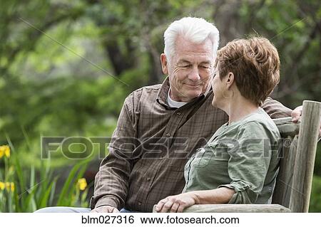 Stock Photograph - Caucasian couple relaxing on bench. Fotosearch