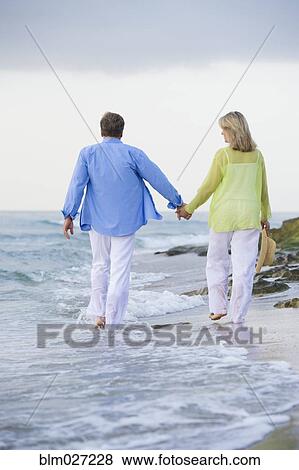 Stock Photo - Caucasian couple walking on beach. Fotosearch