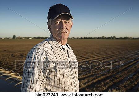 Caucasian farmer standing in irrigated field View Large Photo Image Stock Photo - Caucasian farmer standing in irrigated field. Fotosearch