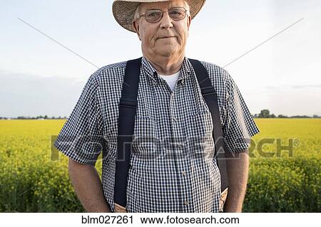 Caucasian farmer standing in mustard field View Large Photo Image Stock Image - Caucasian farmer standing in mustard field. Fotosearch