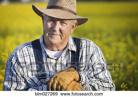 Caucasian farmer standing in mustard field View Large Photo Image Stock Photo - Caucasian farmer standing in mustard field. Fotosearch