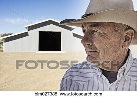 Stock Photo - Caucasian farmer standing outside barn. Fotosearch
