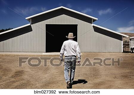 Stock Image - Caucasian farmer walking to barn. Fotosearch