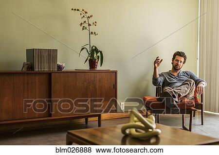 Caucasian man relaxing in living room View Large Photo Image Stock Photo - Caucasian man relaxing in living room. Fotosearch