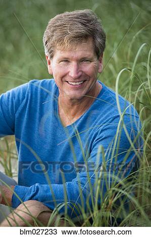 Caucasian man sitting in tall grass View Large Photo Image Stock Image - Caucasian man sitting in tall grass. Fotosearch
