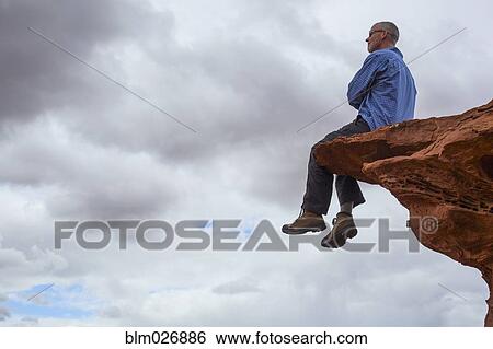 Caucasian man sitting on cliff edge View Large Photo Image Stock Photograph - Caucasian man sitting on cliff edge. Fotosearch
