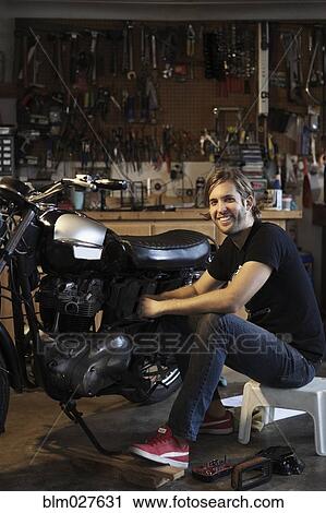 Stock Image - Caucasian mechanic working on motorcycle. Fotosearch
