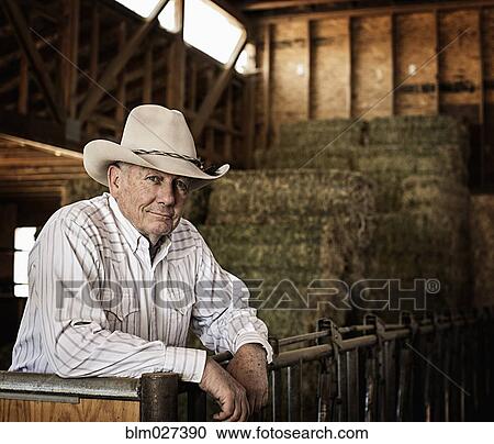 Stock Image - Caucasian rancher standing in barn. Fotosearch