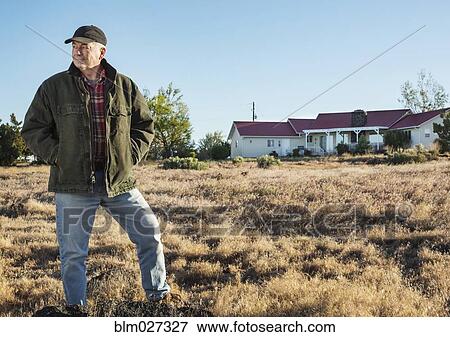 Stock Photo - Caucasian rancher standing in field. Fotosearch