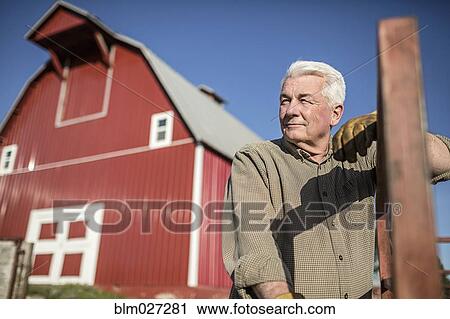 Stock Image - Caucasian rancher standing near barn. Fotosearch